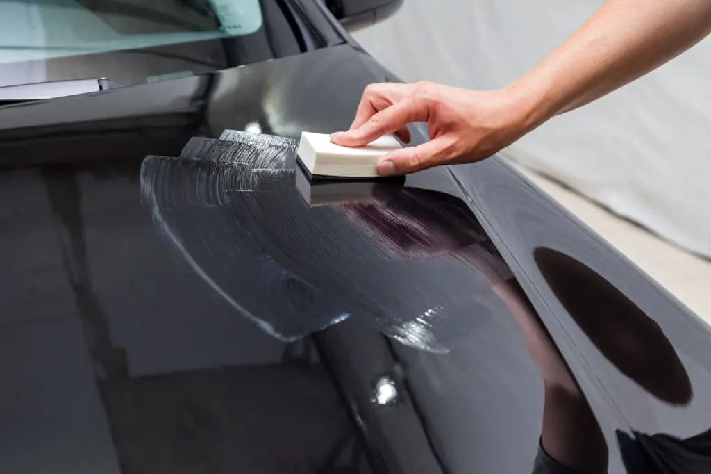 Ceramic coating being applied to dark car paint