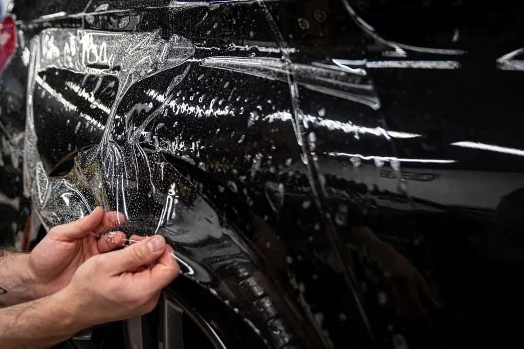 Clear paint protection film being laid on a car panel