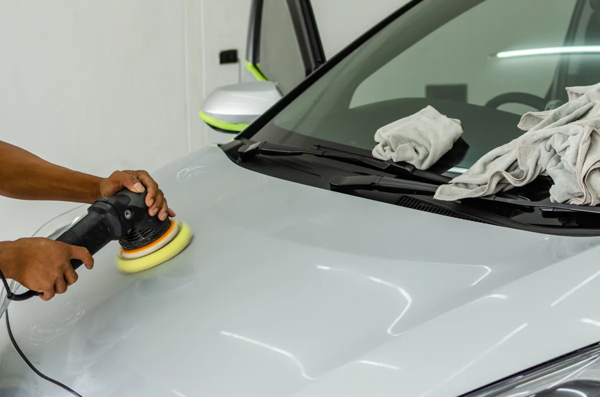 Dual action machine polisher correcting the paint on a silver car hood
