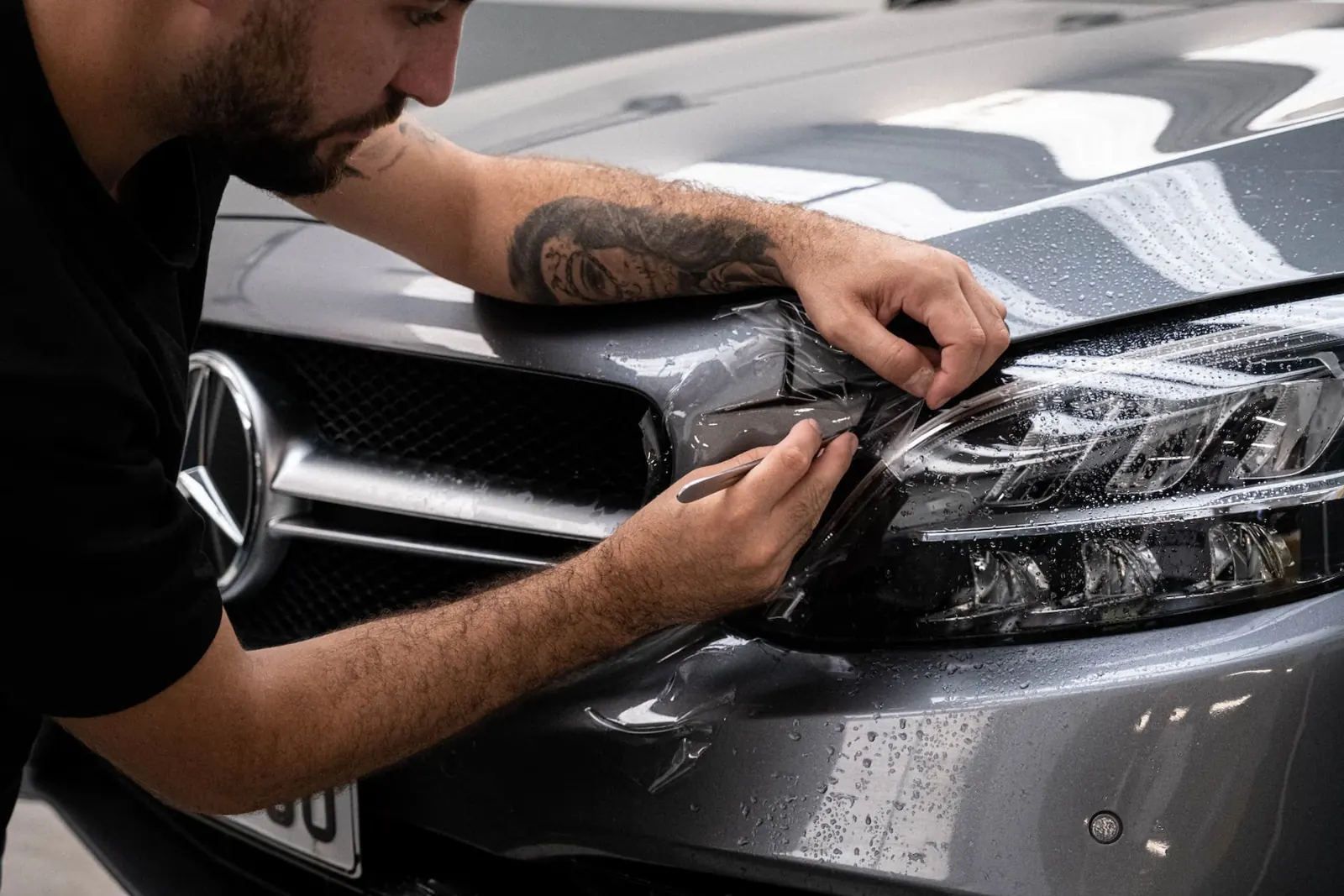 Installer working vinyl wrap film around a car headlight