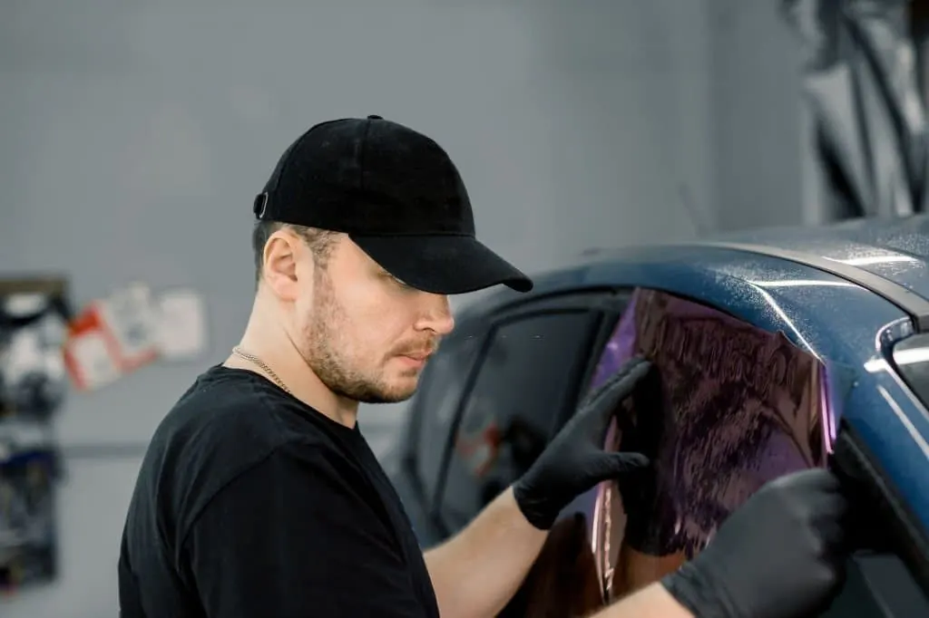 Installer fitting window film to a rear door window